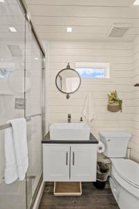W białej łazience znajduje się umywalka i lustro. w obiekcie New! Luxury Shipping Container The Desert Escape w mieście Fredericksburg