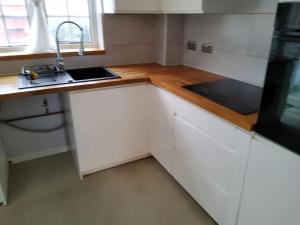 a kitchen with white cabinets and a sink at Primrose lodge cosy 2 bedroom house in a quiet in Norwich