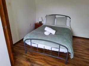 - un lit avec une couette verte et 2 serviettes dans l'établissement Primrose lodge cosy 2 bedroom house in a quiet, à Norwich