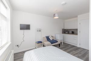 20 Leys Road rooms 1 - 4 في ويلينغبوره: غرفة نوم بيضاء مع سرير ومطبخ