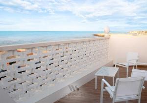 Un balcón con sillas, una mesa y el océano en WHITE SOFIA - uno sguardo sul mare, en Bari