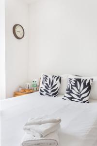 uma cama com duas almofadas e um relógio na parede em City Center Camden Market Budget Apartment and Rooms em Londres