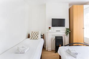 Duas camas num quarto com televisão e lareira em City Center Camden Market Budget Apartment and Rooms em Londres