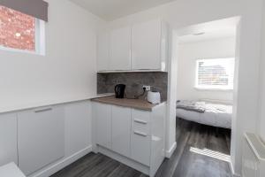 uma cozinha com armários brancos e uma cama em 20 Leys Road rooms 1 - 4 em Wellingborough