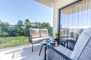 Un balcón con una silla y mesas y una gran ventana. en Apartments Villa V2, en Vir