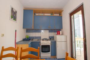 eine Küche mit blauen Schränken und einem weißen Kühlschrank in der Unterkunft Apartments Barbara in Pakoštane