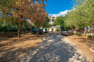 a dirt road with cars parked on the side of a building at Apartments Barbara in Pakoštane +6 photos
