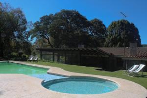 ein Pool mit zwei Gartenstühlen und ein Haus in der Unterkunft La Pedra Hotel Boutique, Raco in Raco