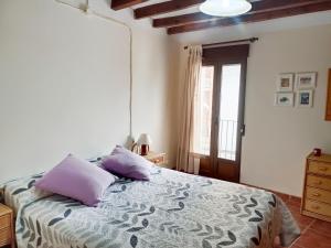 a bedroom with a bed with purple pillows and a window at Ca l'Èndula II in Lucena del Cid