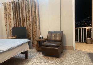 1 dormitorio con silla, 1 cama y TV en Outdoor Adventures Resort en Muzaffarābād