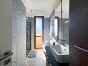 een badkamer met een witte wastafel en een spiegel bij Urban Penthouse - Milan & Rho Fiera in Bresso