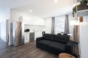 uma sala de estar com um sofá preto e uma cozinha em Modern Home Near Town em Dunedin