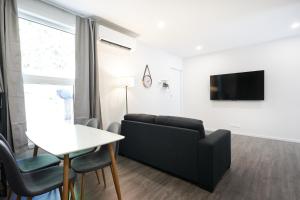 uma sala de estar com um sofá preto e uma mesa em Modern Home Near Town em Dunedin