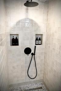 a white tiled bathroom with a shower with a hose at Maison UMI 