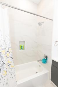 a white bathroom with a tub and a sink at Modern Contemporary 2-Bed Apt Close to NYC in Bayonne