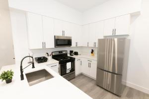 a kitchen with white cabinets and a stainless steel refrigerator at Modern Contemporary 2-Bed Apt Close to NYC in Bayonne