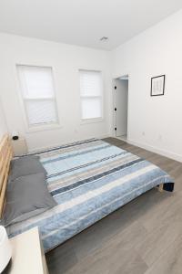 a large bed in a white room with windows at Modern Contemporary 2-Bed Apt Close to NYC in Bayonne