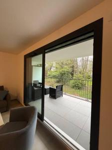 een woonkamer met een glazen schuifdeur naar een patio bij Appartement proche de Genève 2 in Collonges-sous-Salève