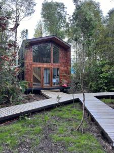 une maison en briques avec une porte en verre dans un jardin dans l'établissement Panigal, à Hornopirén