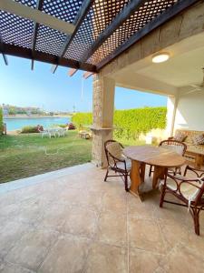 Un patio al aire libre con una mesa y sillas de madera. en فيلا أول صف على البحيرة مارينا 5ج2, en El Alamein