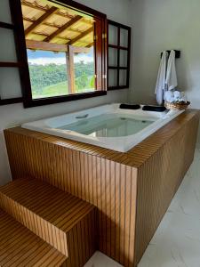 a large bath tub in a room with a window at Pousada Vista Pedra Azul in Pedra Azul