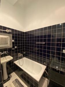 La salle de bains est pourvue de carrelage noir, d'une baignoire et d'un lavabo. dans l'établissement Mieszkanie obok Pałacu Goetza BRZESKO, à Brzesko