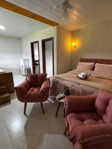 a bedroom with a large bed and two chairs at Pousada Vista Pedra Azul in Pedra Azul