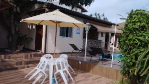 a patio with two white chairs and an umbrella at Casa c/ Piscina e Área Gourmet, 5 min da praia. in Guarapari