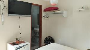 1 dormitorio con TV de pantalla plana en la pared en Casa c/ Piscina e Área Gourmet, 5 min da praia., en Guarapari
