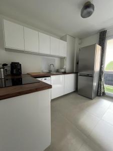 a kitchen with white cabinets and a stainless steel refrigerator at Appartement Cosy et Confortable in Saint-Genis-Laval