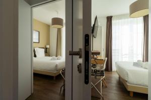 サン・ナゼールにあるベスト ウェスタン ホテル デ ラ プラージュ サンマルク シュル メールのベッド2台とデスクが備わるホテルルームです。