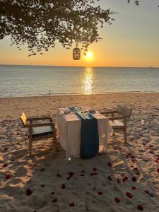 Haad Pleayleam的住宿－Siam Cookies Cottage，海滩上的一张桌子,背靠日落