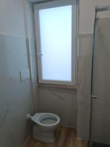 a bathroom with a toilet with a window and a shower at La Casa di Ary in Cisterna di Latina