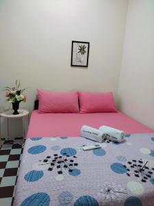 a pink bed with two pillows and a rug at Santai HomeStay Sipitang in Sipitang