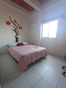ein Schlafzimmer mit einem Bett und einer Vase mit Blumen an der Wand in der Unterkunft HOTEL SANTA VERONICA INN in Santa Veronica