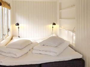 uma cama branca com quatro almofadas em cima em Holiday home Jægerspris XXXII em Jægerspris