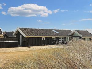 a brown house with a fence and a house at Four-Bedroom Holiday home in Løkken 28 in Lønstrup