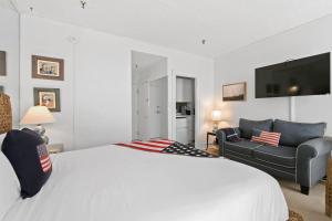 una camera con un grande letto bianco e un divano di Tropicals of Palm Beach a Palm Beach