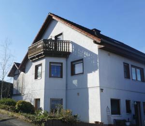 a white house with a balcony on top of it at Ferienwohnung Hüppelröttchen in Eitorf