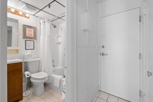 a white bathroom with a toilet and a shower at Tropicals of Palm Beach in Palm Beach