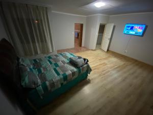MOMENTS Of JOY GUESTHOUSE AND SPA AT CARNIVAL في Brakpan: غرفة نوم بسرير وتلفزيون بشاشة مسطحة