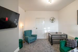 a living room with a tv and a chair and a table at HugeDiscounts Monthly offers in Gateshead