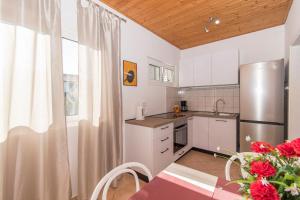 a kitchen with white cabinets and a table with red flowers at Apartments Andrija in Pirovac