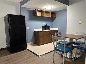 een keuken met een zwarte koelkast en een tafel en stoelen bij HomeTowne Studios by Red Roof Richmond, VA - W Broad St in Richmond +14 foto's