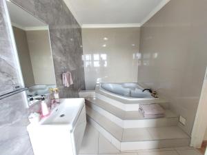 een witte badkamer met een bad en een wastafel bij View On 3rd in Centurion