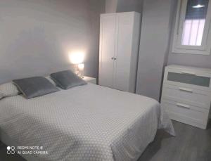 a white bedroom with a bed and a window at Estudio Palacio Congresos Aeropuerto in Seville