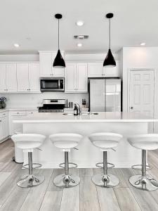 a white kitchen with white cabinets and bar stools at NEW Luxurious 5BR/3BATHES Home, Spacious and Retreat location with Modern Amenities in Ontario