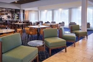 ein Esszimmer mit Tischen, Stühlen und einem Tisch in der Unterkunft Courtyard by Marriott Detroit Livonia in Livonia