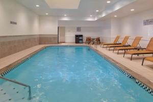 a large swimming pool with chairs in a hotel room at Courtyard by Marriott Detroit Livonia in Livonia