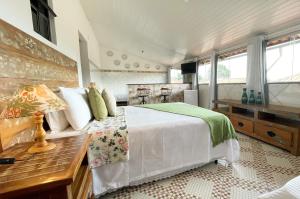 a bedroom with a bed and a desk and windows at Pouso das Flores -350m Maria Fumaça in Tiradentes